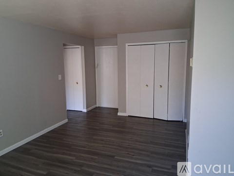 A room with a wooden floor and white cupboards.
