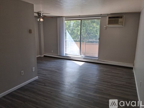 A room with wooden flooring and a sliding glass door leading to a balcony.
