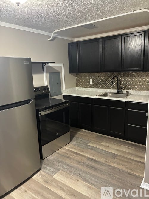 A kitchen with black cabinets and a stainless steel refrigerator.