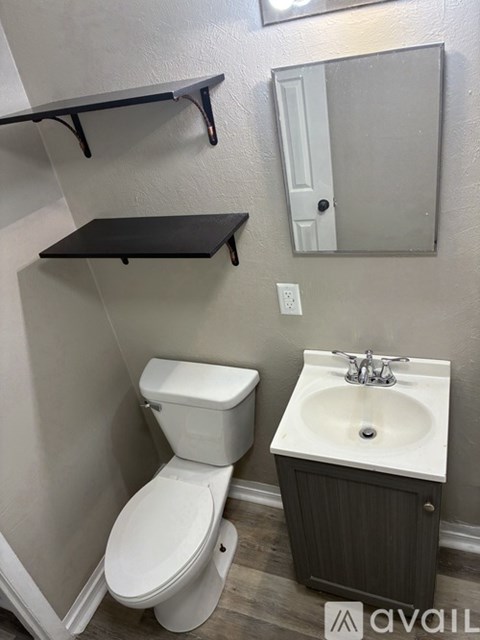 A bathroom with a toilet, sink, and mirror.