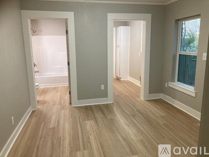 A room with wooden flooring and two open doors.