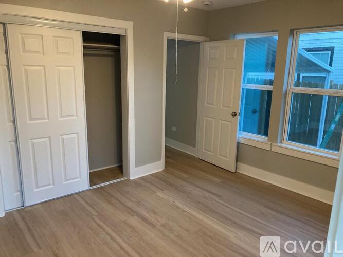 A room with a white door and a window with a view of a house.
