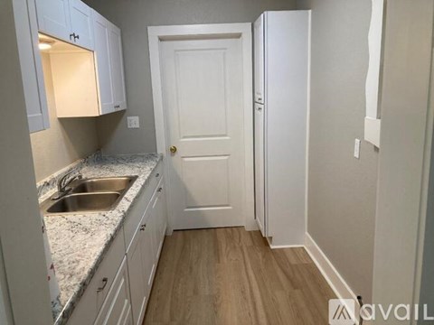 A kitchen with white cabinets and a white door.