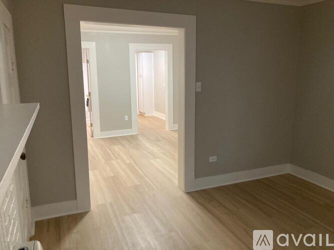 A hallway with light wood flooring and white walls.