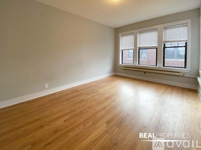 A room with wooden flooring and a window with blinds.