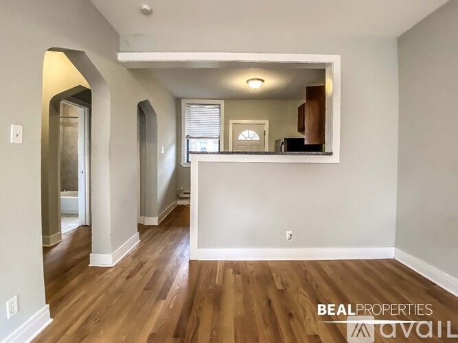 A spacious room with wooden floors and a large mirror on the wall.