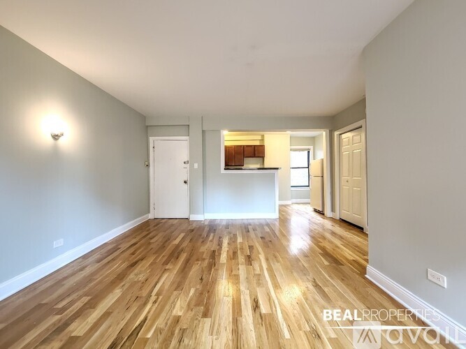 A spacious room with wooden flooring and white walls.
