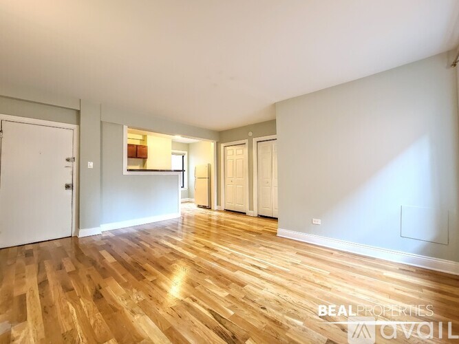 A room with wooden flooring and white walls, with a door on the left and another door on the right.