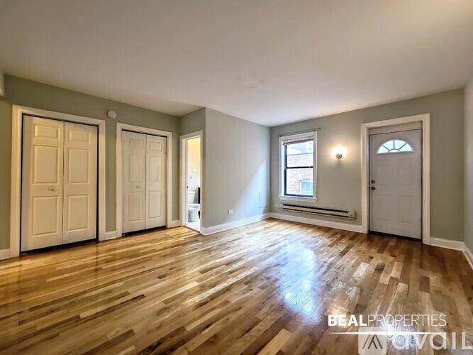 A room with wooden floors and white walls, with a window on the right wall.