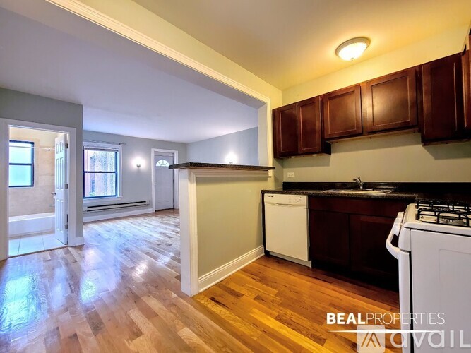 A kitchen with a white dishwasher and wooden floors.