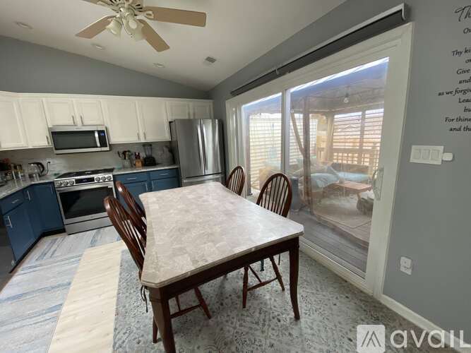 A kitchen with a table and chairs in front of a sliding glass door.