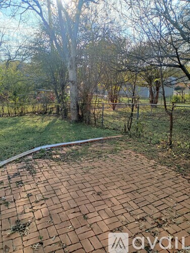 A brick pathway leads through a grassy area with trees.