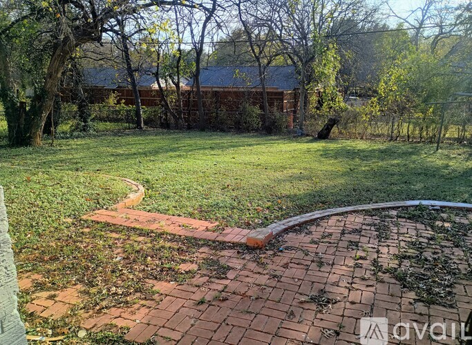A backyard with a brick walkway and a grassy area.
