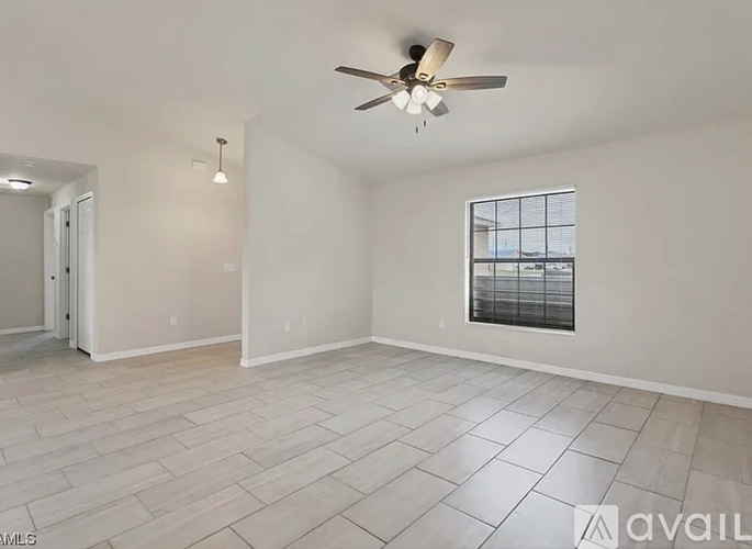 A spacious room with a ceiling fan and a window with blinds.
