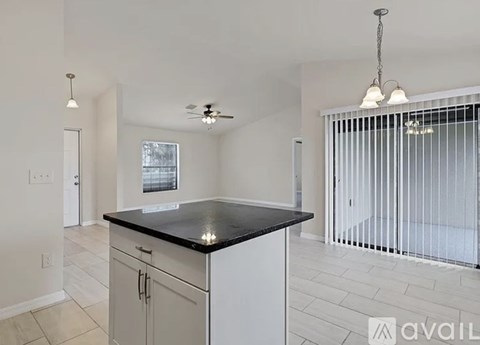 A kitchen with white cabinets and a black countertop.