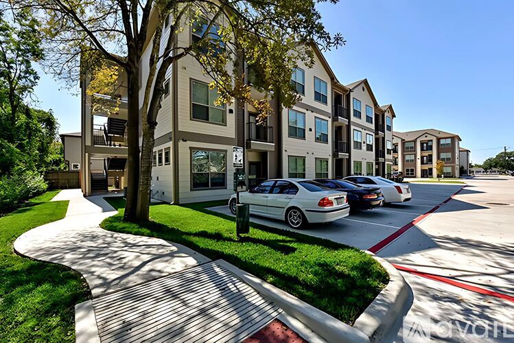 A row of modern townhouses with cars parked in front.