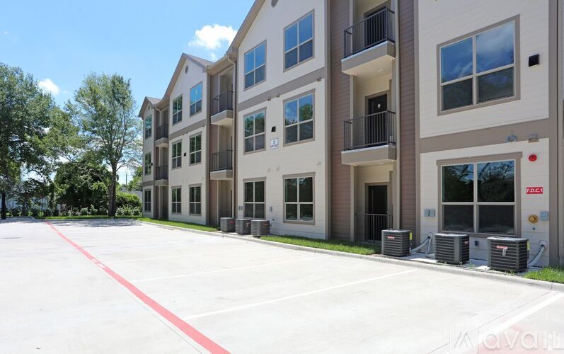 A large parking lot in front of a multi-story apartment building.