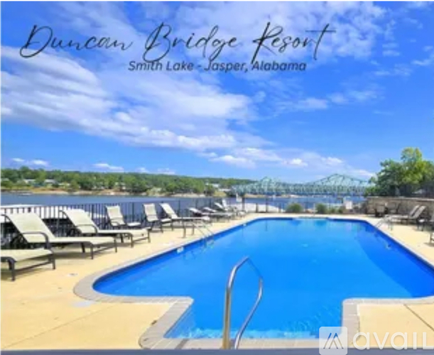 A pool at the Duncan Bridge Resort with lounge chairs and a view of a bridge in the distance.