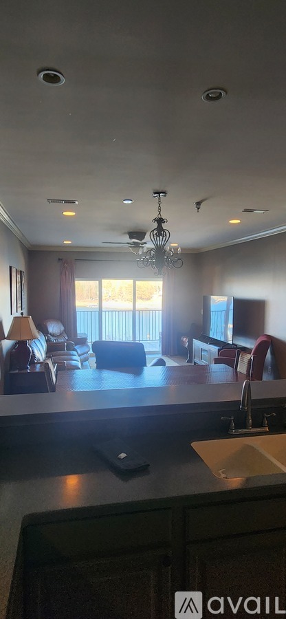 A kitchen with a black counter top and a chandelier hanging from the ceiling.