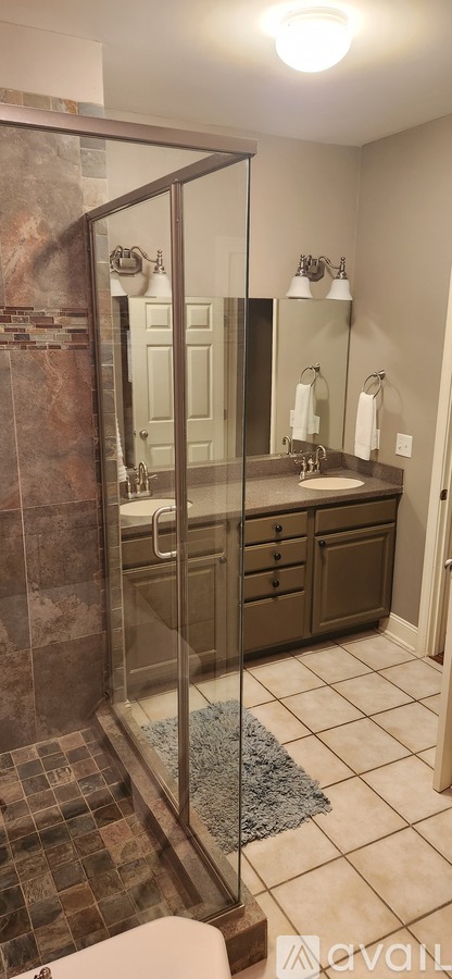 A bathroom with a glass shower door and a tiled floor.