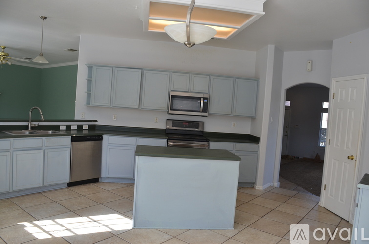 A kitchen with white cabinets and a black countertop.