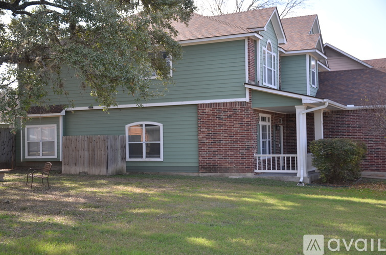 A house with a green siding and a brick chimney.