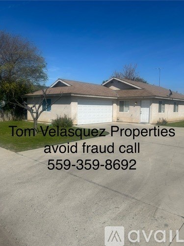 A house with a sign that says "Tom Velasquez Properties avoid fraud call 559-359-8692".