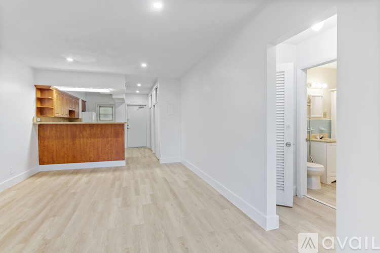 A spacious room with wooden flooring and white walls.