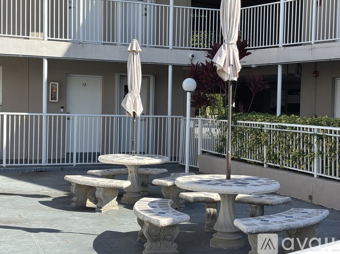 A patio with tables and umbrellas in front of a building.