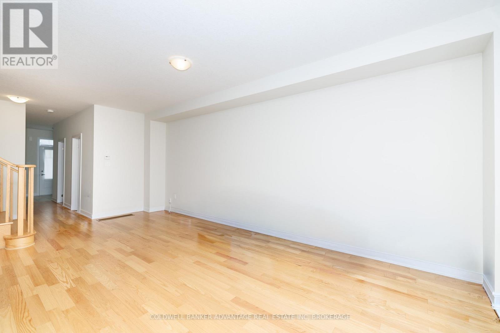 A spacious room with wooden flooring and white walls.