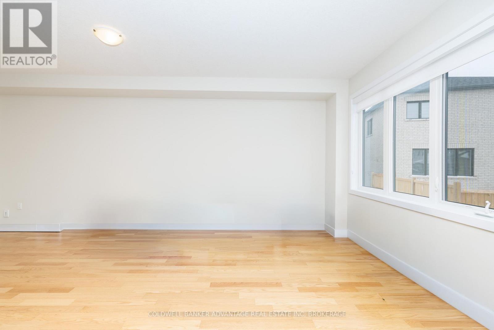 A room with wooden flooring and a window showing a building outside.