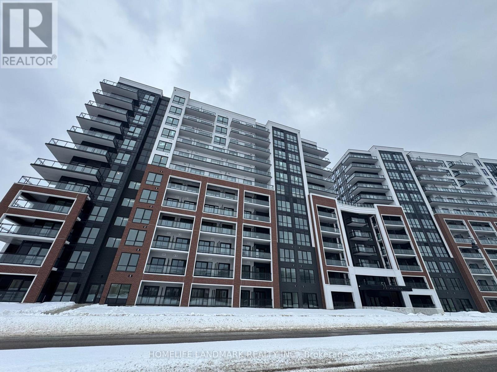 A large, modern apartment building with multiple balconies and a snowy ground.