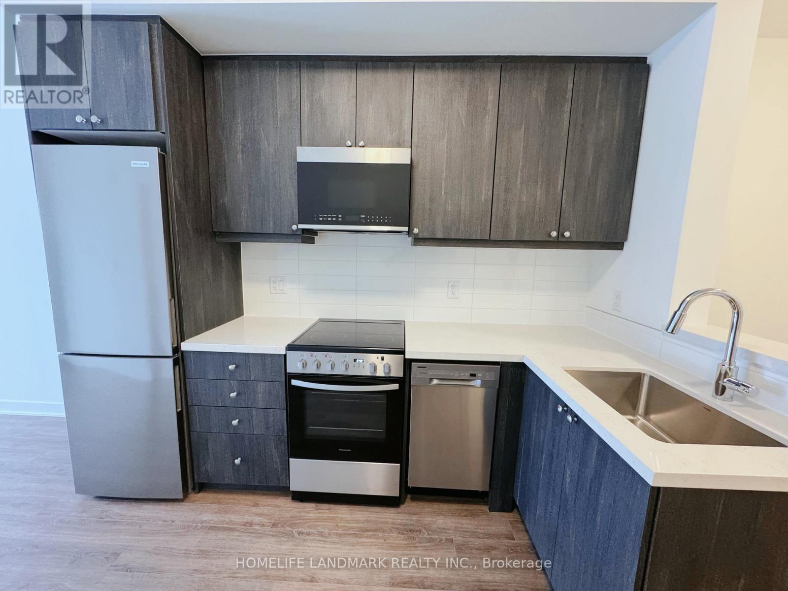 A modern kitchen with a refrigerator, oven, dishwasher, and microwave.