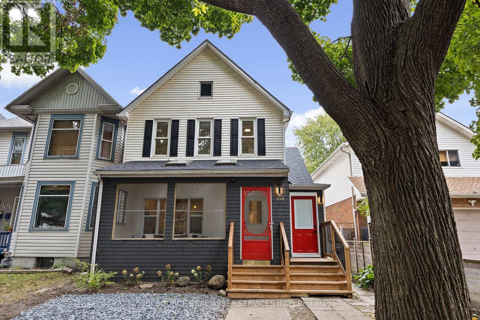 A house with a red door and a tree in front.