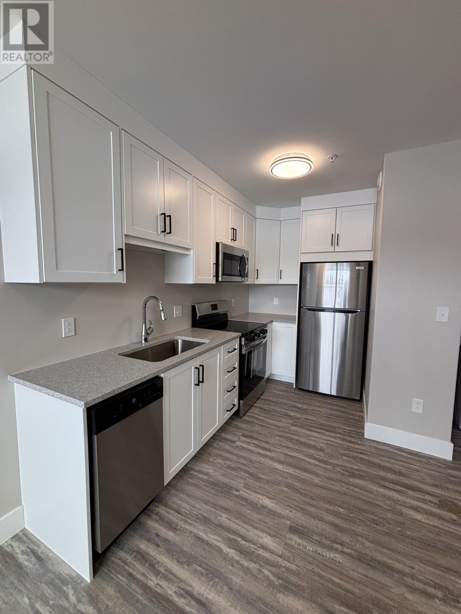 A kitchen with white cabinets and a grey countertop.