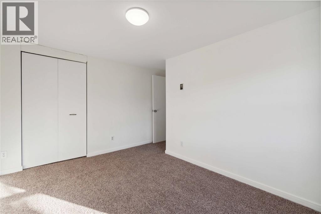 A bedroom with a carpet and a white door.