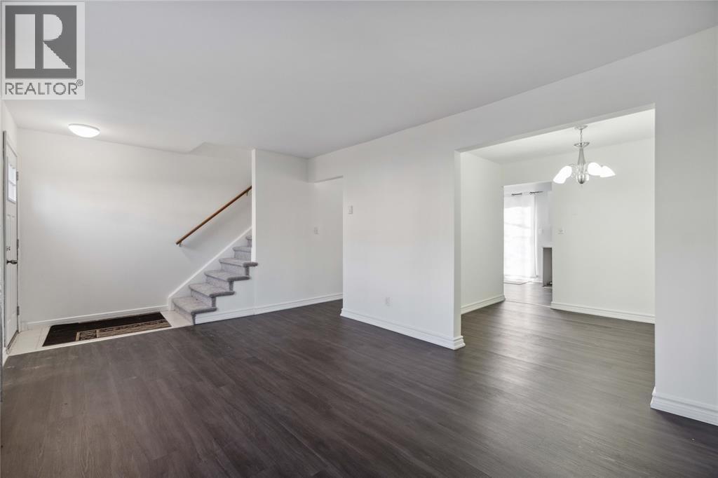 A spacious room with a staircase and a door leading to another room.