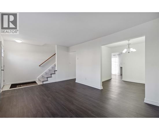A spacious room with a staircase and a door leading to another room.