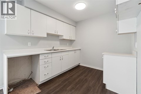 A kitchen with white cabinets and a brown floor.