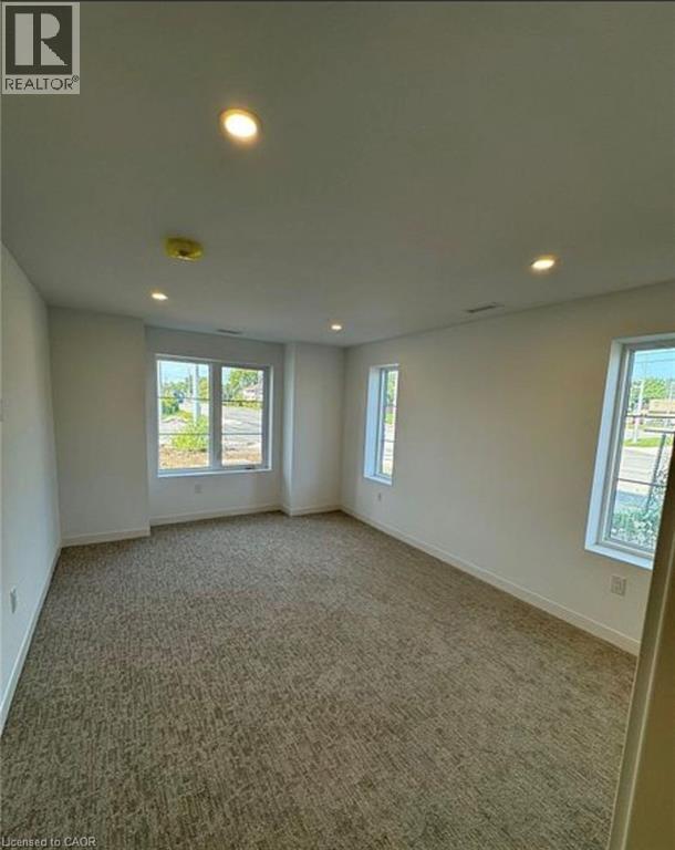 A large empty room with carpeted floor and windows.