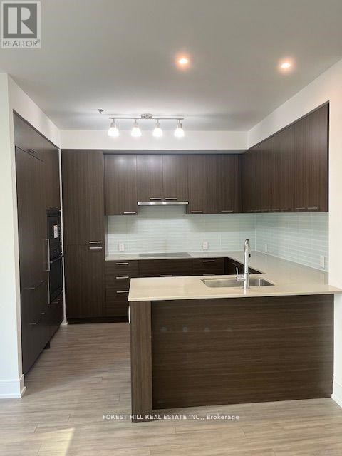 A modern kitchen with dark wood cabinets and a white countertop.