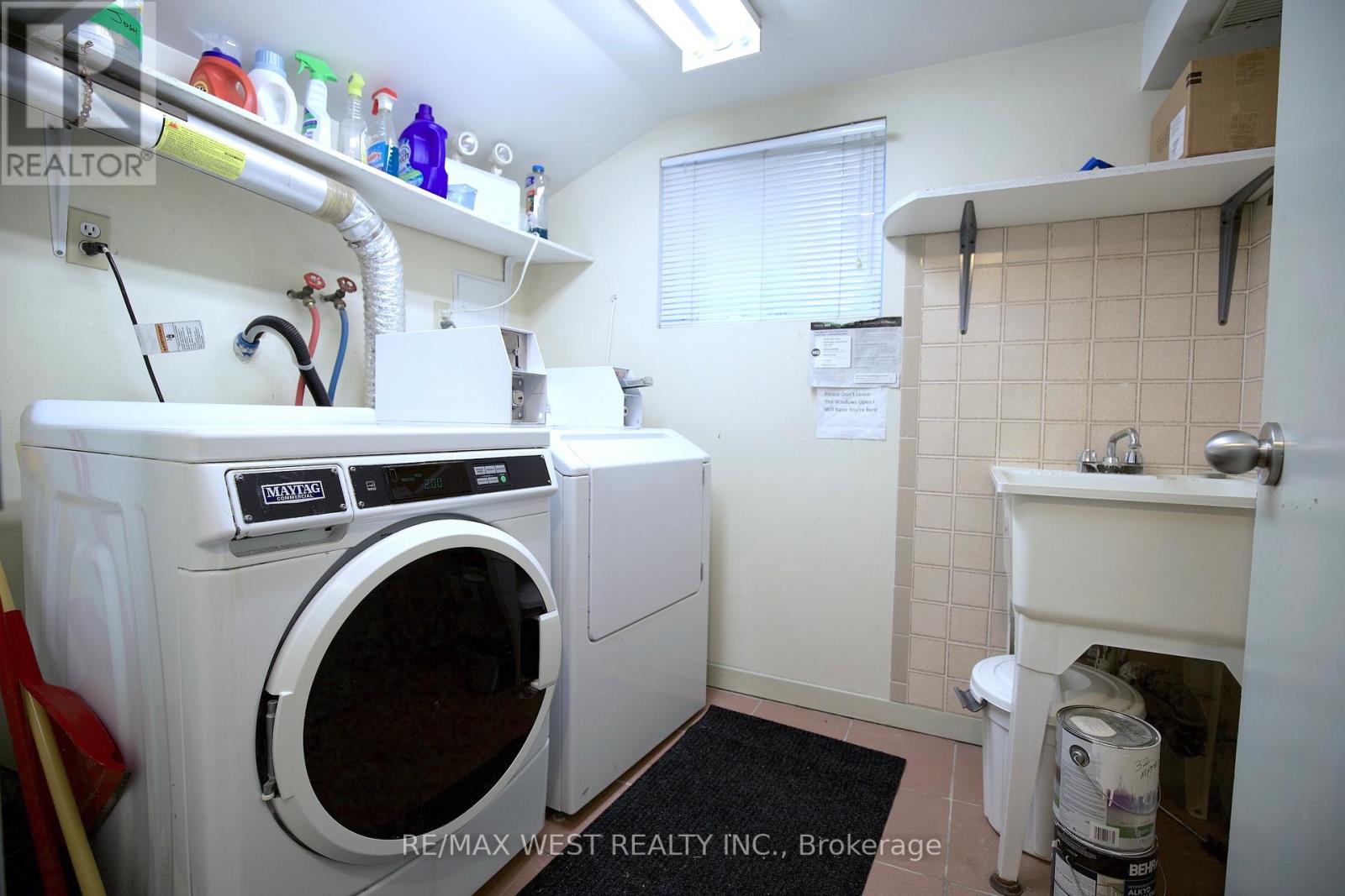 A laundry room with a washer and dryer, a sink, and a window.