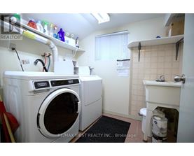 A laundry room with a washer and dryer, a sink, and a window.