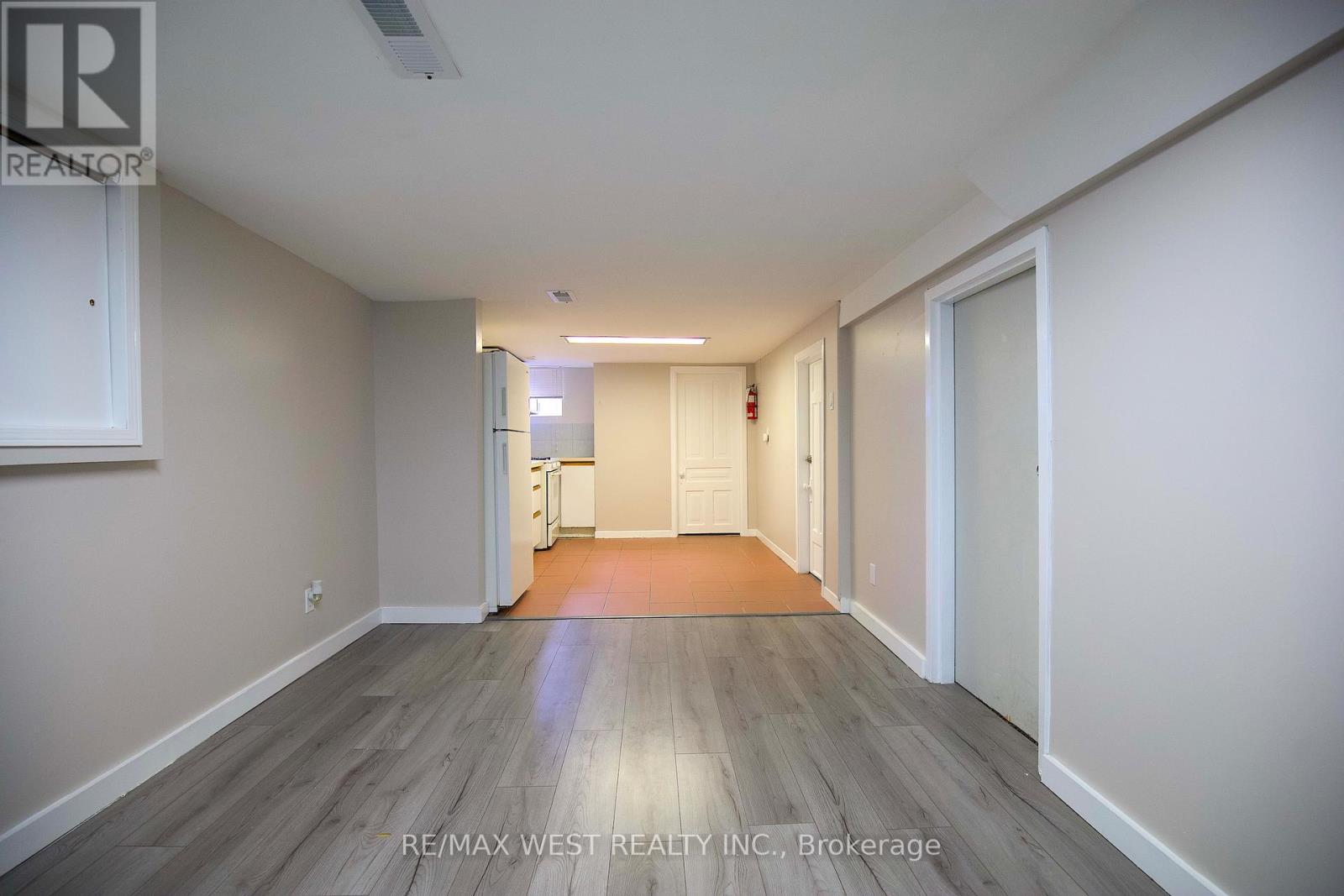 A spacious room with wooden flooring and white walls.