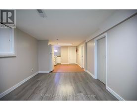 A spacious room with wooden flooring and white walls.