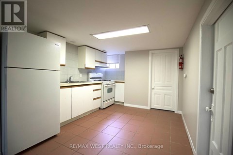A kitchen with white appliances and brown tile flooring.