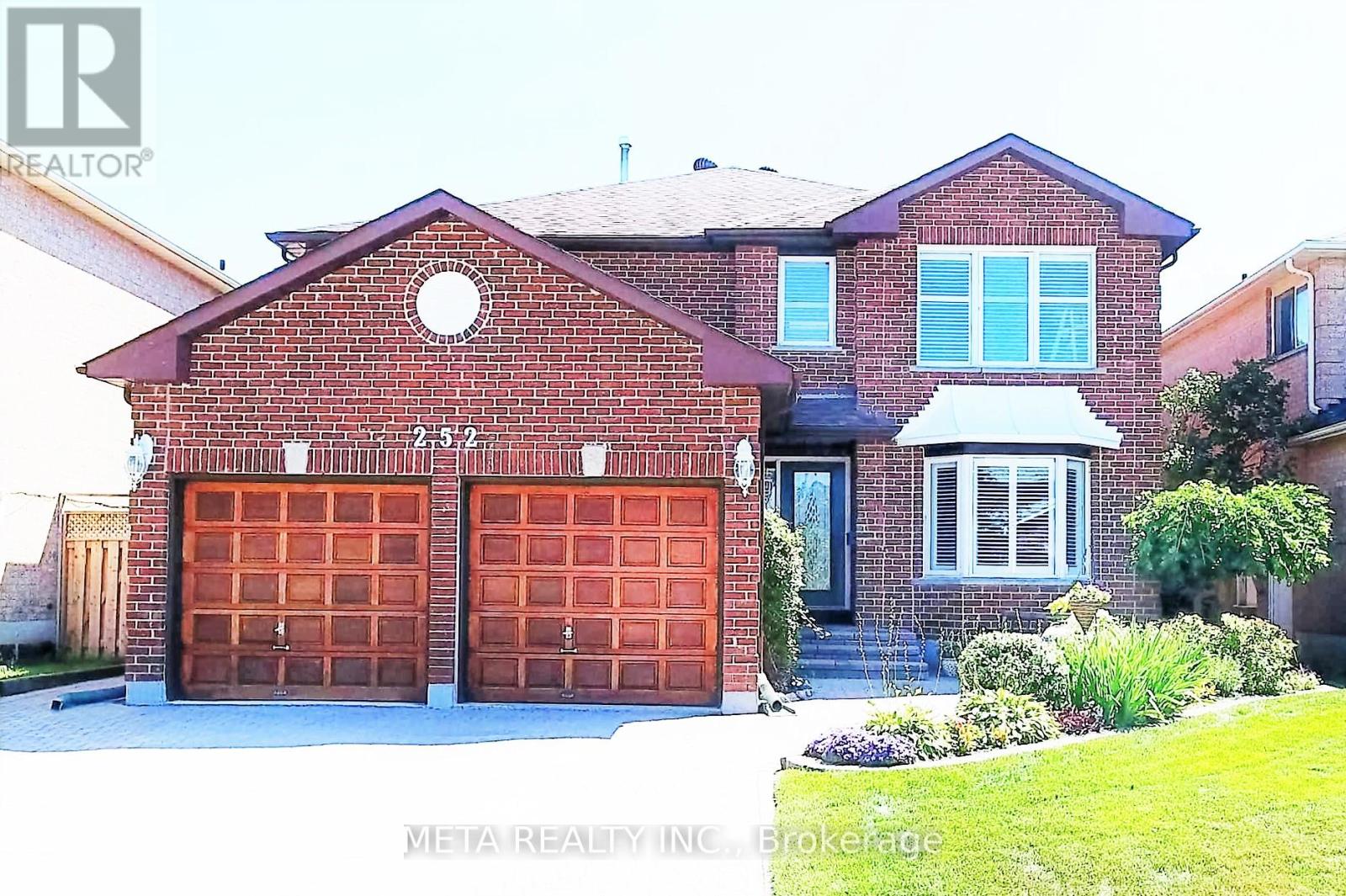 A red brick house with two garage doors.