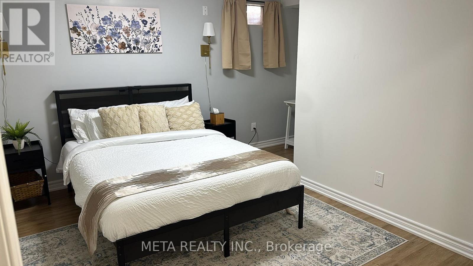 A bedroom with a large bed and a painting on the wall.