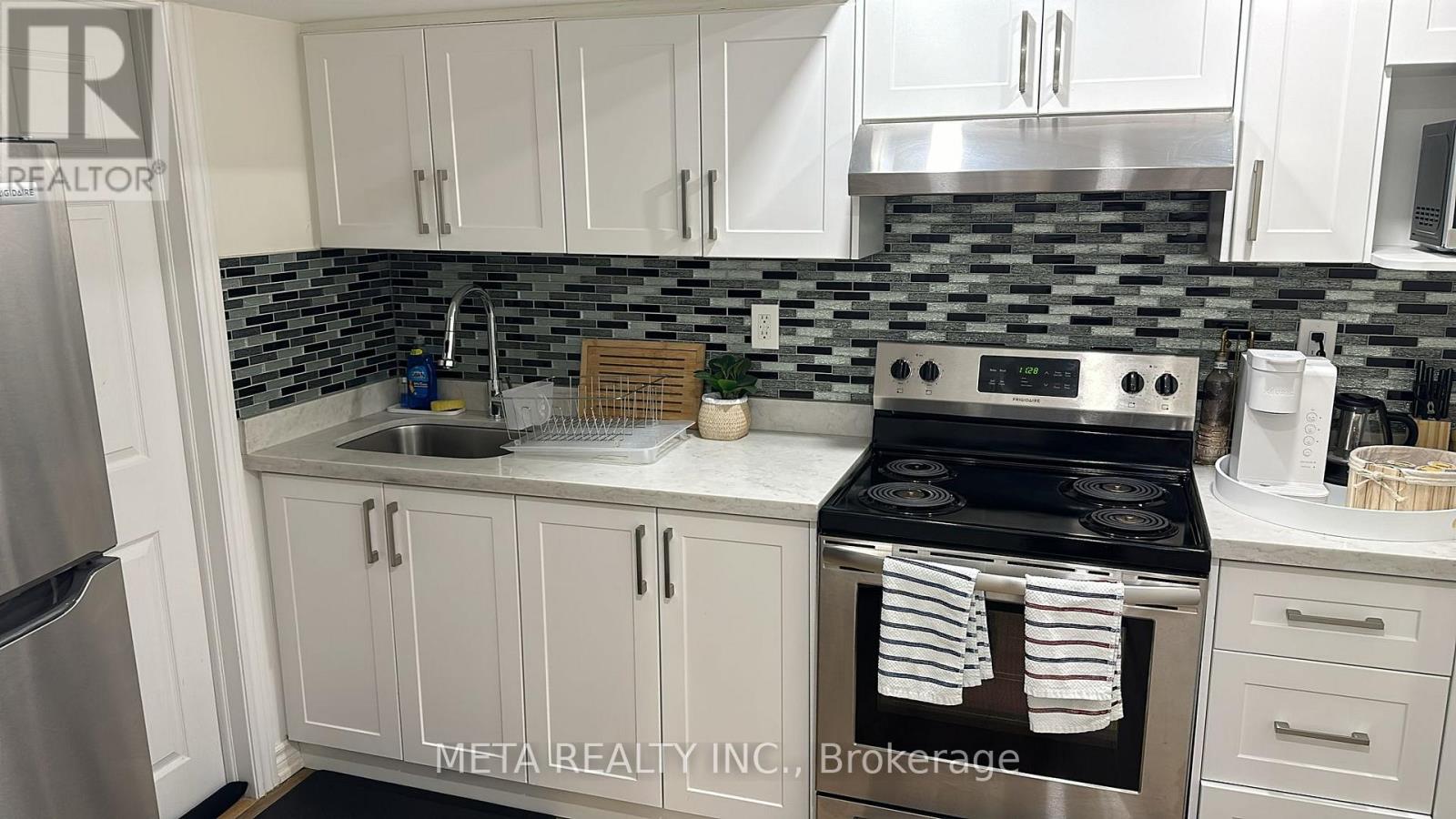 A kitchen with a stove top oven and a refrigerator.