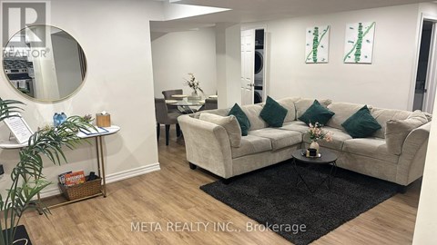 A living room with a white couch and a black rug.
